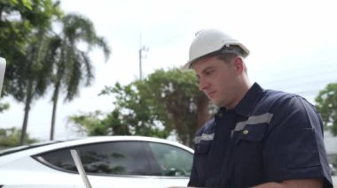 Evde EV şarj istasyonu kurulumu üzerinde çalışan nitelikli teknisyen, EV için dizüstü bilgisayarla şarj sisteminde sorun çıkarma ve yapılandırma ayarları yapıyor. Titiz