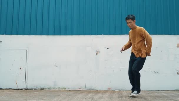 西班牙裔男子伸出胳膊 在墙前跳舞 穿着休闲装的舞者或编舞家的动作镜头 练习嘻哈风格的男孩舞 户外运动2024 — 图库视频影像