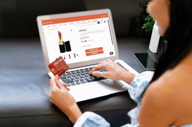 Genç bir kadın internet bankacılığı için kredi kartıyla dizüstü bilgisayar kullanıyor. Evinde online ödeme kapısı ile E ticareti yapıyor. Banka kartıyla modern ve kullanışlı online alışveriş. Blithe