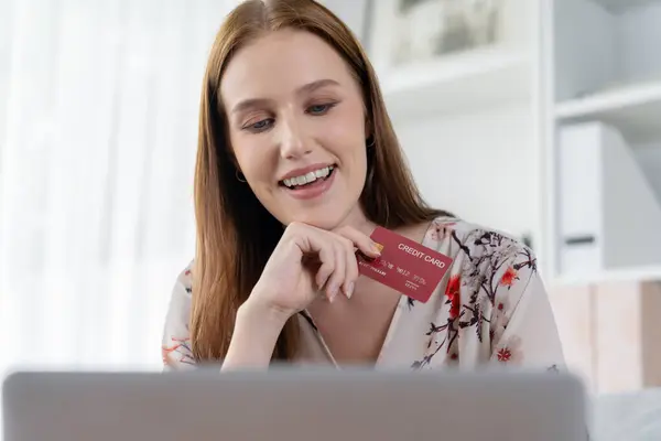 Young happy woman buy product by online shopping at home while ordering items from the internet with credit card online payment system protected by utmost cyber security from online store platform