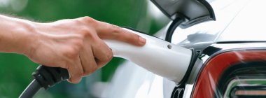 Yakından el yerleştirme ve şarj etmek için EV şarj cihazı şarj istasyonundan şarj ediliyor. Alternatif enerji, gelecekteki sürdürülebilirlik için çevre dostu taşımacılığında kullanılıyor. Eşzamanlama