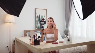 Sosyal medya için güzellik ve kozmetik video içeriği hazırlayan genç bir kadın. Güzellik blogcusu kameraya gülümserken seyircilere ve takipçilere güzellik bakımını gösteriyor. Düzenle
