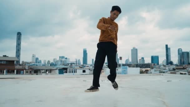 街头舞蹈演员在屋顶上的B Boy舞蹈表演与天空碎屑 城市景观 迷人的亚洲嬉皮士表现出精力充沛的步伐 霹雳舞练习街舞 户外运动2024 — 图库视频影像
