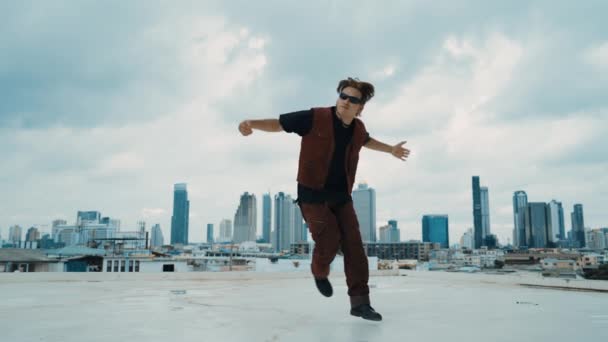 Boy舞蹈表演由专业街头舞者在屋顶上与天空碎屑 城市景观 迷人的亚洲嬉皮士表演 迈着充满活力的步伐 2024年户外运动 Hip Hop风格 Hiphop — 图库视频影像