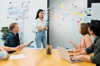 Genç ve güzel lider pazarlama stratejisini sunarken, uzman yatırımcı ve proje yöneticisi de yeni başlayan iş toplantısında iş performansını analiz etmeye çalışıyor. Çok ırklı bir grup. Tertemiz..