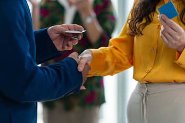 İş adamları el sıkışıyor ve anlaşma işareti olarak iş kadınıyla iş birliği yapıyor. Yöneticilerin kartvizit tutarken çekilmiş görüntüleri. Ortakları arkada duruyor. Entelektüel.