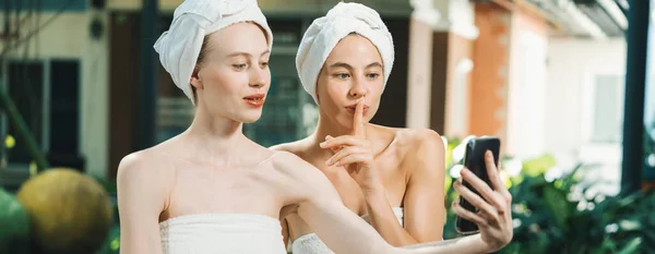 stock image Couple of young beautiful women with beautiful skin in white towel taking a photo together at outdoor surrounded by peaceful natural environment. Beauty and healthy spa concept. Tranquility.