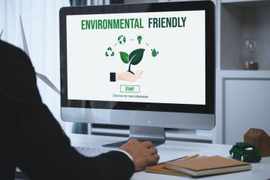 Ofiste çalışan iş adamı, CSR 'ın dışında daha yeşil bir çevre için bilgisayar ekranında güneş pili teknolojisiyle çevre dostu alternatif enerji planı veya projesi geliştiriyor. Döngü