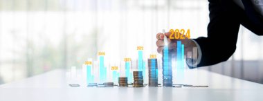 Büyüyen madeni para yığını iş yatırımını ve ekonomik büyümeyi simgeliyor. Finansal hedefe ulaşmak ve 2024 yılına maksimum kar sağlamak için finansal planlama yapan iş adamları. Kurnaz.