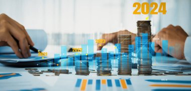 Büyüyen madeni para yığını iş yatırımını ve ekonomik büyümeyi simgeliyor. Finansal hedefe ulaşmak ve 2024 yılına maksimum kar sağlamak için finansal planlama yapan iş adamları. Kurnaz.