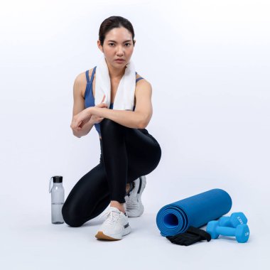 Atletik ve sportif Asyalı kadın yoğun kardiyo antrenmanından sonra dinleniyor. Stüdyoda sağlıklı egzersiz ve vücut bakımına uygun yaşam tarzı takibi izole edilmiş bir arka plan. Kuvvetli