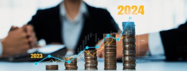 Büyüyen madeni para yığını iş yatırımını ve ekonomik büyümeyi simgeliyor. Finansal hedefe ulaşmak ve 2024 yılına maksimum kar sağlamak için finansal planlama yapan iş adamları. Kurnaz.