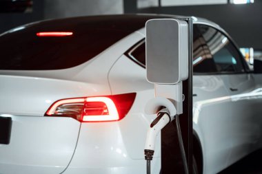 Alış veriş merkezinin otoparkında EV elektrikli araba şarjı şehir merkezindeki sürdürülebilirlik yaşam tarzını yeşil, temiz, yeniden şarj edilebilir elektrikli araç iç organları ile gösteriyor.