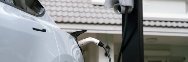 Elektrikli taşıt teknolojisi, EV araba aküsünün şarj edilmesi için konut istasyonunda kullanılıyor. Gelecekteki çevre için temiz ve sürdürülebilir enerji ile çevre dostu ulaşım. Panorama Senkronizasyonu