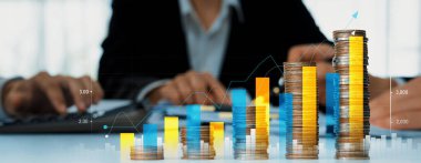 Dijital grafik göstergeli bozuk para yığını iş yatırımını ve ekonomik büyümeyi sembolize ediyor. Finansal hedefe ulaşmak ve kâr sağlamak için finansal planlama yapan bir iş adamı. Kurnaz.