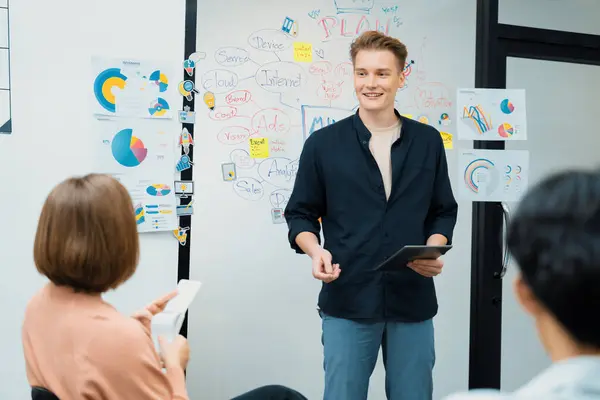 Professional male leader presents start up project by using mind map, colorful sticky notes and business statistic graph with confident while investor listening at business meeting. Immaculate.