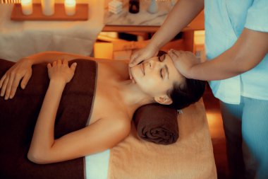Beyaz kadın stres önleyici kafa masajı yapmaktan ve lüks otel veya otelde sıcak mum ışığında yüz güzelliği eğlencesi yapmaktan zevk alıyor. Sessiz.