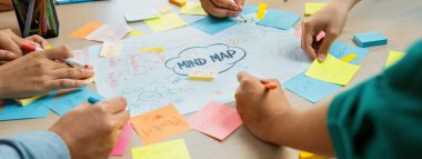 Profesyonel başlangıç grubu zihin haritası kullanarak yaratıcı pazarlama fikrini paylaşıyor. Genç yetenekli iş adamları yapışkan notlar yazarken beyin fırtınası planı yapıyorlar. Eline odaklan. - Yakın çekim. Değiştirilmiş.