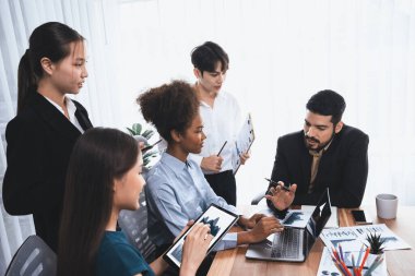 Çok ırklı analist ekibi toplantı masasındaki finansal verileri analiz etmek için BI Fintech yazılımı kullanıyor. Finansal konsol veri ekranında pazarlama göstergesi için analiz edilmiş grafikle birlikte. Uyum