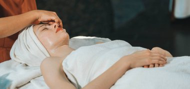 Elektrikli güzellik ekipmanlarıyla çevrili spa yatağında uzanmış güzel, beyaz bir kadın yüz masajı yaptırıyor. Güzellik maskesi. Spa salonunda tıbbi malzemelerle çevrili. Huzur.