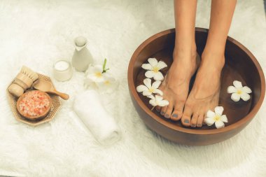 Panorama üstteki kadın lüks spa salonunda mutlu bir ayak masajı yaparken, masör de hafif gündüz atmosfer tesisinde veya otel ayak spasında refleksoloji terapisi uyguluyor. Sessiz.