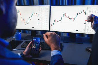 İki borsa simsarı akıllı telefon ve dinamik dijital para birimi dizüstü bilgisayar sunucusu verilerini araştırıyor. Yatırımcılar, işyerinin dekoratif neon mavi ışığındaki pazar hisselerini analiz ediyorlar. Satılabilir.