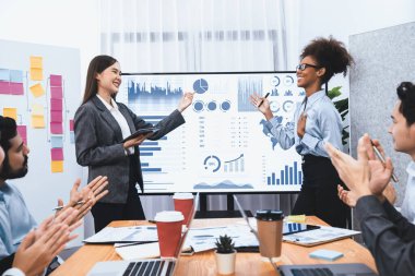 İş adamları TV ekranında başarılı bir sunum veya veri analizi toplantısından sonra kutlama yapıyorlar. Mutlu takım ofis odasında toplanıyor, kutlama jestleriyle işbirliği için tezahürat yapıyorlar. Uyum