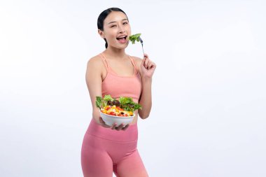 Spor giyim mağazasında elinde meyve ve sebze dolu salata kasesi tutan genç bir Asyalı kadın. Doğal gençlik ve uygun vücut yaşam tarzı izole edilmiş arka planda dengeli beslenme. Kuvvetli