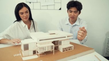 Profesyonel akıllı iş birliği mühendisi mühendis ekibi modern ofisteki ev yapısını planla kontrol ederken genç ve güzel proje yöneticisi not alıyor. Yaratıcı tasarım konsepti. Tertemiz...