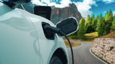 Elektrikli araç konsepti, yeşil çevre için yenilenebilir ve temiz enerjiyle çalışan EV otomobilinin varış noktasına ulaşmadan önce ormandaki şarj istasyonunun enerjisini şarj etmek için durur..