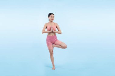 Spor kıyafetli Asyalı bir kadın antrenman yaparken ayakta durarak yoga egzersizi yapıyor. Sağlıklı vücut bakımı ve meditasyon yoga yaşam tarzı izole bir arka planda. Kuvvetli