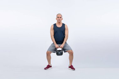 Vücut uzunluğu tam, atletik ve sportif yaşlı bir adam izole edilmiş arka planda vücut çalışması için kettlebell ile hiçbir şey yapmıyor. Emeklilikten sonra sağlıklı, aktif bir fiziğe ve vücut bakımına sahip. Etki