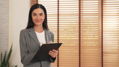 Mutlu ve gülümseyen kadın psikolog psikiyatri ofisinde ya da terapi odasında pano tutuyor. Arkadaş canlısı ve profesyonel ruh sağlığı danışmanı ya da terapisti. Blithe