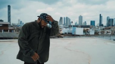 Profesyonel B-boy dansçısı, profesyonel sokak dansçısı. Çatıda gökyüzü dövüşçüsü, şehir manzaralı. Çekici Asyalı hipster enerjik adımlar atıyor. Break dans. Açık hava sporu 2024 hiphop..