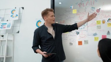 Profesyonel erkek lider projeye zihin haritası, renkli yapışkan notlar ve iş istatistiksel grafiği ile yatırımcı elini kaldırarak ve soru sorarak başlıyor. Tertemiz..