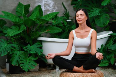Sabah yoga ve meditasyon yapan genç bir kadın bitki yaprağıyla doğal bahçede yalnızlığın tadını çıkarıyor ve meditasyon yapıyor. Farkındalık aktivitesi ve sağlıklı zihin yaşam tarzı. Blithe