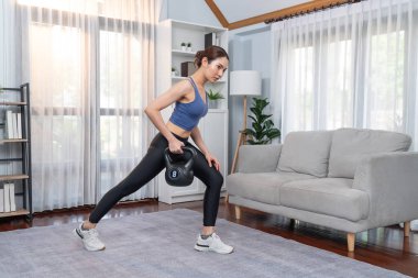 Enerjik kadın evde kettlebell ağırlık kaldırma egzersizi yapıyor. Genç atletik Asyalı kadın dayanıklılığı ve dayanıklılık antrenmanı. Ev ödevi olarak..