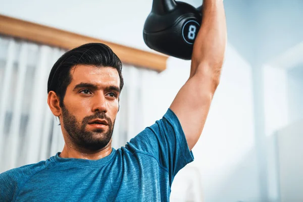 健康的なフィットボディホームワークアウトライフスタイルのコンセプトとして 効果的なターゲティング筋肉の利益のためのケトルウェイトを持ち上げる運動体とアクティブスポーティな男性 — ストック写真