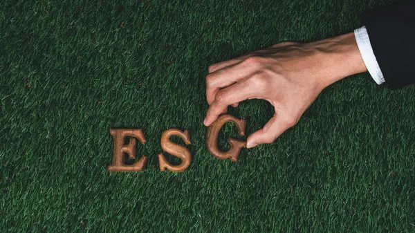 Environmental awareness campaign showcase message arranged by hand in ESG on biophilic green grass background. Environmental social governance concept idea for sustainable and greener future. Gyre