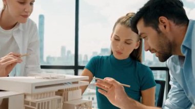 Beyaz proje yöneticisi dizüstü bilgisayar analiz verilerini kullanırken, mimar mühendis ekibi ev modeli inşaatını analiz etmek için birlikte çalışıyor. Bir grup tasarımcı ev tasarımı hakkında konuşuyor. İzleme