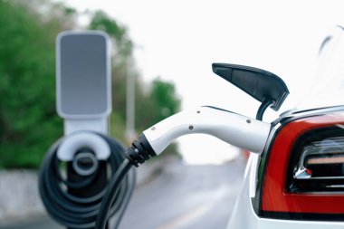 Kapalı EV şarj kolu fişe takıldı veya elektrikli arabaya bağlandı, EV araba aküsünü temiz çevre için sıfır CO2 emisyonu ile alternatif ve sürdürülebilir enerjiyle şarj etti. Kalıcı