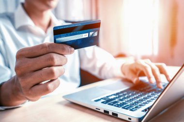 Genç adam, laptop bilgisayar başvurusu ya da web sitesinde online alışveriş yapmak için kredi kartı kullanıyor. E-ticaret ve online alışveriş konsepti. uds