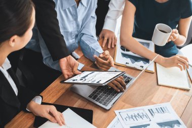 Çok ırklı analist ekibi toplantı masasındaki finansal verileri analiz etmek için BI Fintech yazılımı kullanıyor. Finansal konsol veri ekranında pazarlama göstergesi için analiz edilmiş grafikle birlikte. Uyum