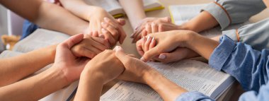 İncildeki ahşap kilisede insanların el ele dua ederken inançla el ele tutuşmalarının kırpılmış görüntüsü. Umut kavramı, din, inanç, Tanrı 'nın lütfu kavramı. Filizlenen.