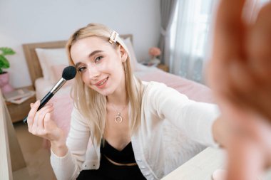 Sosyal medya için güzellik ve kozmetik video içeriği hazırlayan genç bir kadın. Güzellik blogcusu, seyircilere ve takipçilere rimel sürmeyi öğretirken kameraya gülümsüyor. Blithe