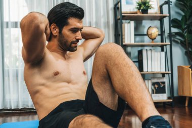 Atletik ve sporcu adam, evde vücut egzersizi yaparken spor ve spor yaşam tarzına uyum sağlamak için spor minderinde çatırdıyor. Gaiety ev egzersizi antrenman konsepti.