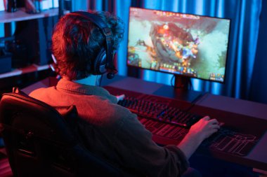 Savaş arenasında çoklu oyunlar takımıyla Moba 'da savaşan genç oyun flamasının sunucu kanalı, neon dijital ışık modern odasındaki arka görüntü ile bilgisayar monitöründe kulaklık takıyor. Toplayıcı.