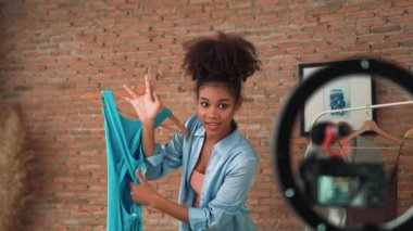 Kadın nüfuzlu kişi canlı yayında video görüntülerini çekiyor. Kıyafetler sosyal medya ya da blog için çok önemli. Stüdyo ışıklandırmalı mutlu genç kız çevrimiçi pazarlama oturumu yayını için..