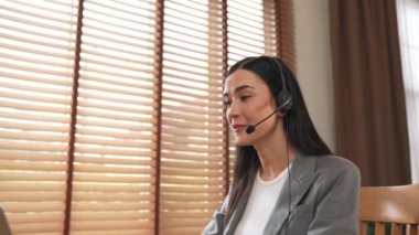 Kadın çağrı merkezi operatörü ya da müşteri hizmetleri çalışanı, müşteriye yardım etmek için kulaklıkla konuşurken çalışma alanı üzerinde çalışıyor. Profesyonel modern iş hizmeti. Blithe