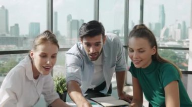 Profesyonel iş ekibi başarılarını kutlarken dizüstü bilgisayar kullanarak iyi haberler alıyor. Müdür, modern ofisteki meslektaşıyla el çırparken dizüstü bilgisayarı işaret ediyor. İzleme